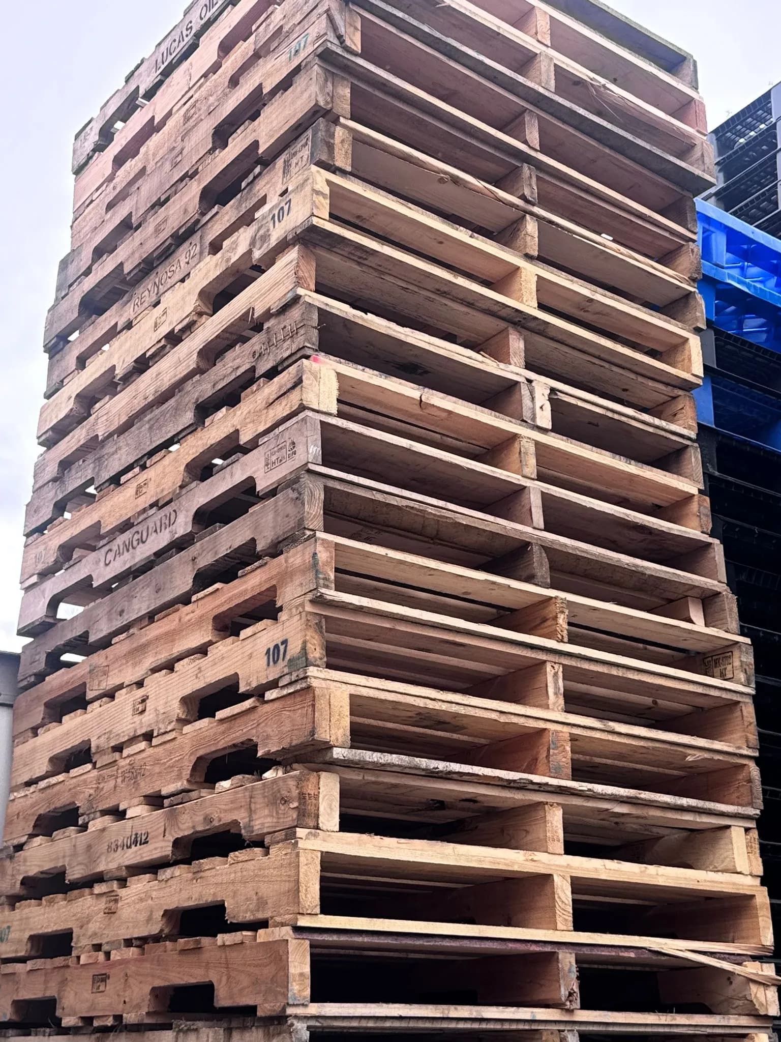 Tall stack of used wooden pallets ready for sorting and grading