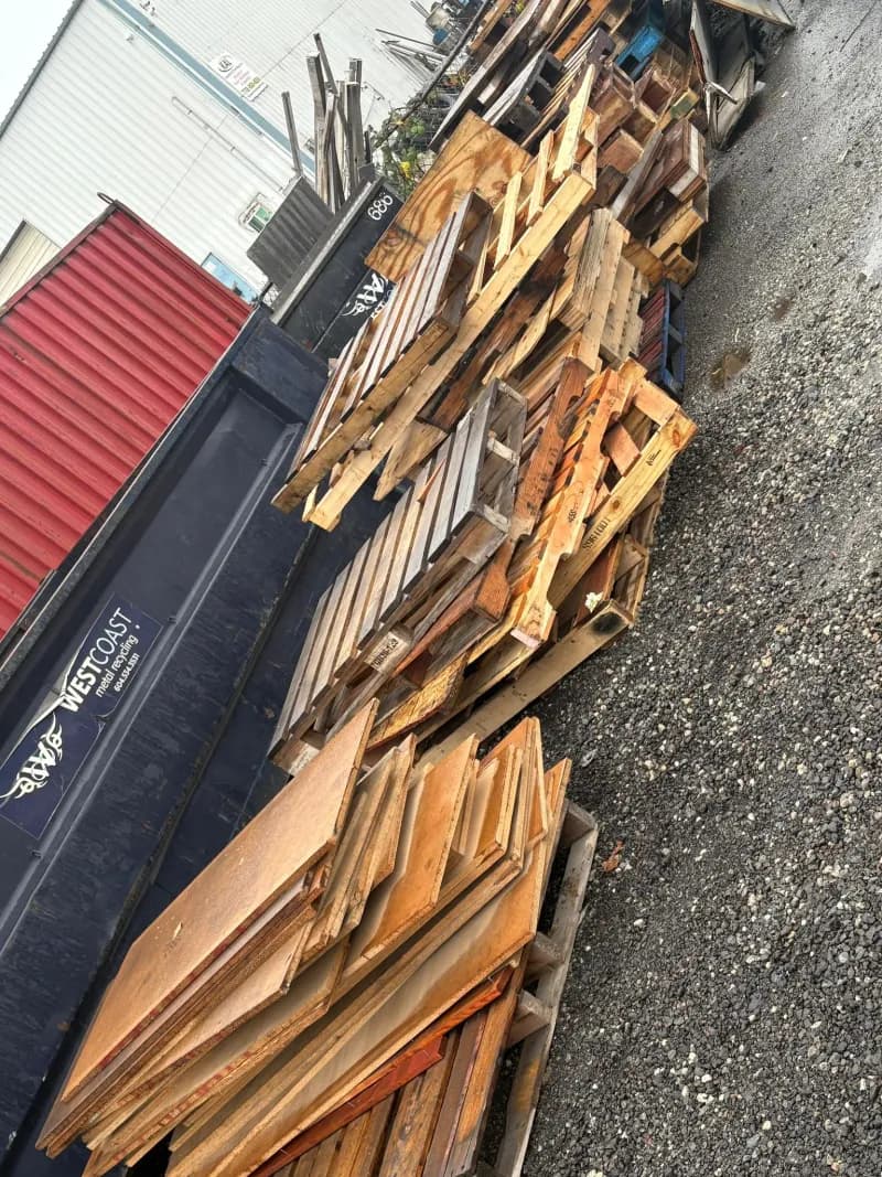 Stacked wooden pallets next to recycling container